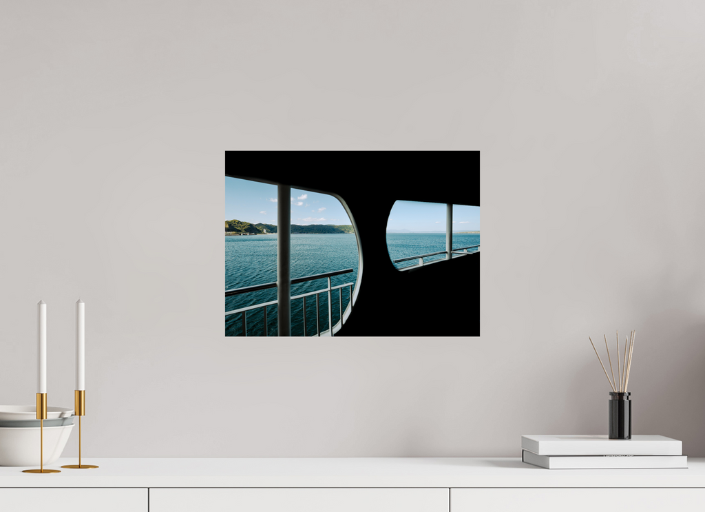 Framed artwork of a scenic view on a white wall above a white surface with decorative items.
