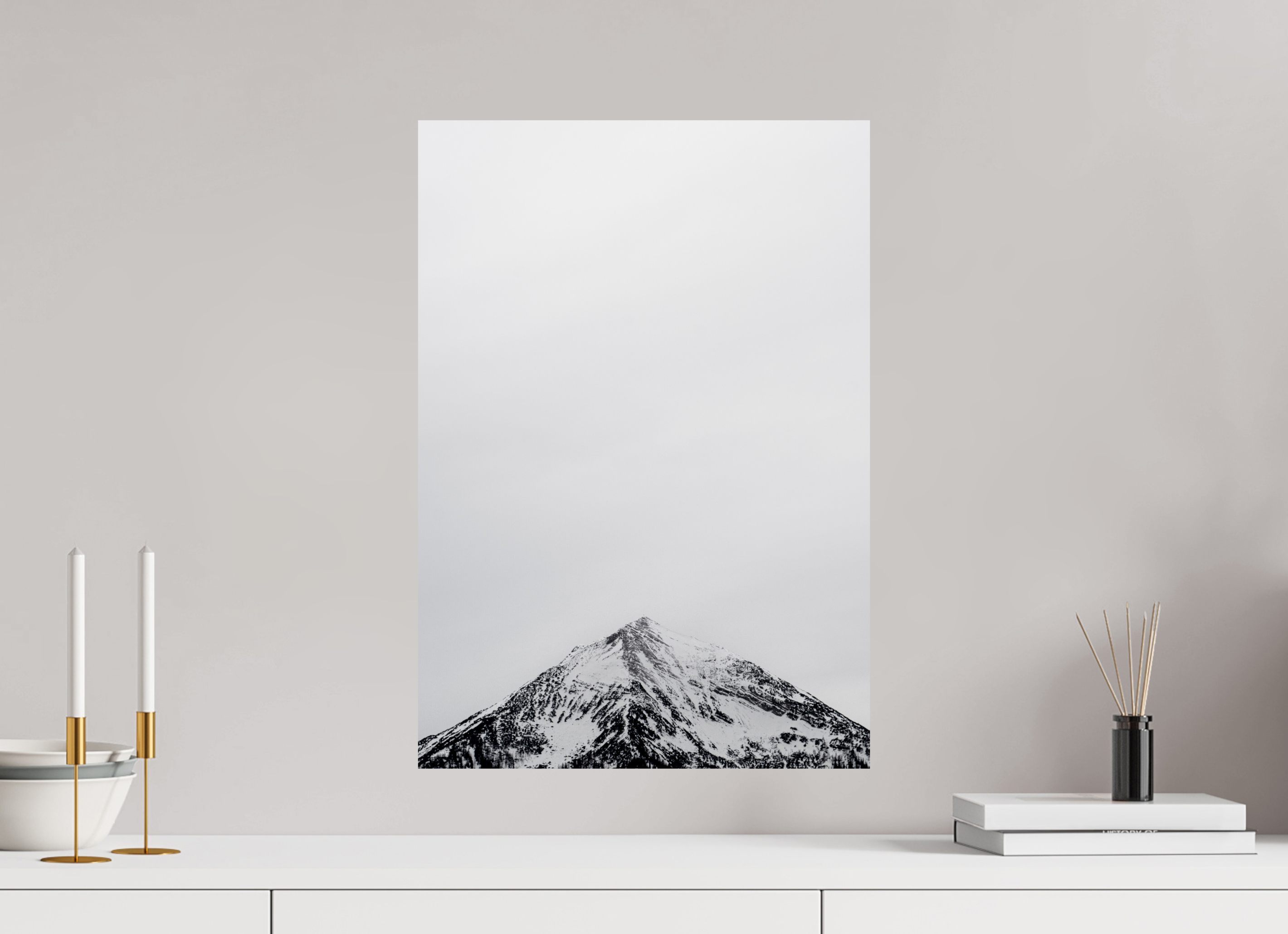 Poster of a mountain landscape on a wall with decorative items below.