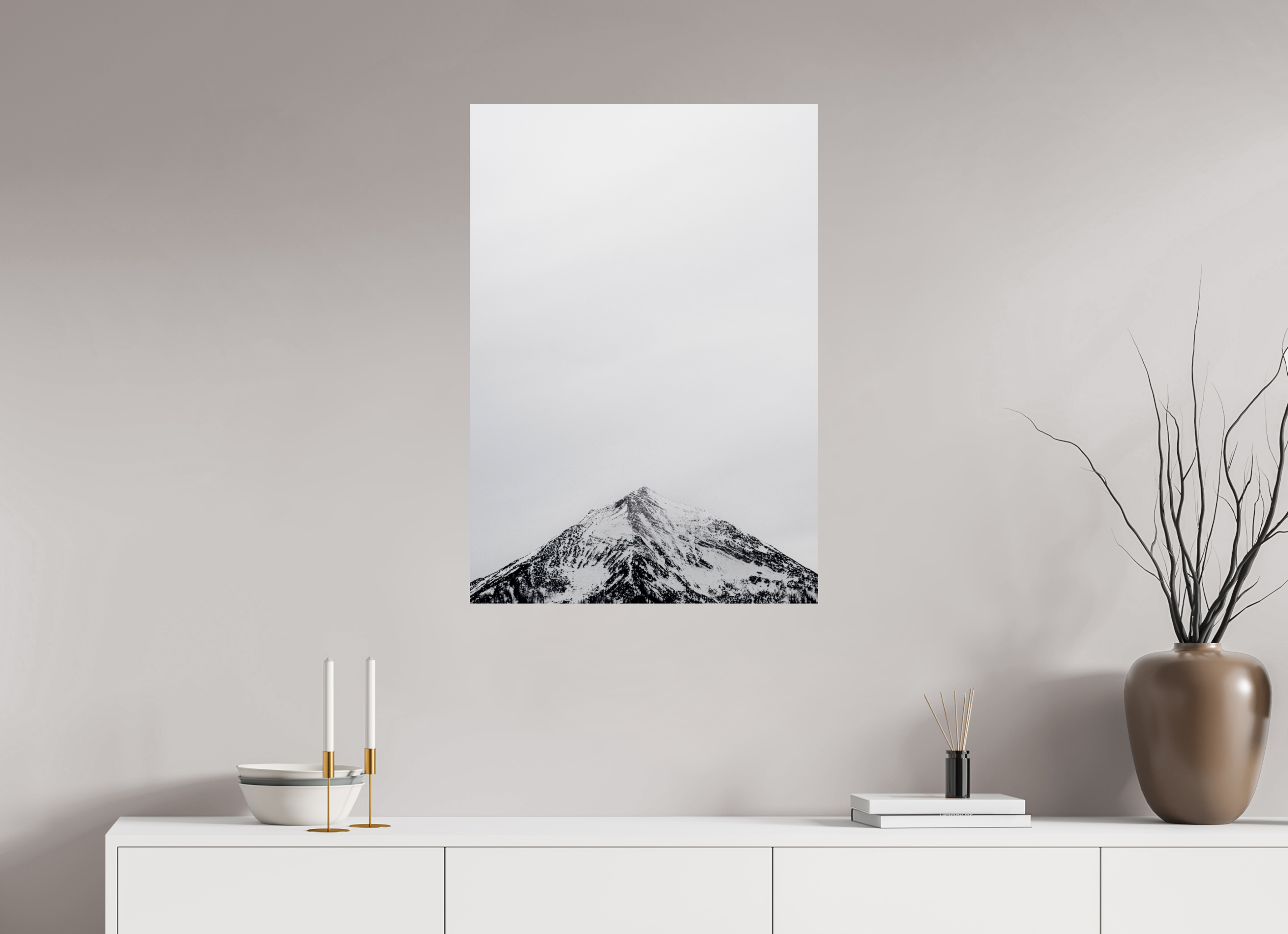 Canvas print of a mountain on a wall above a white cabinet with decorative items.