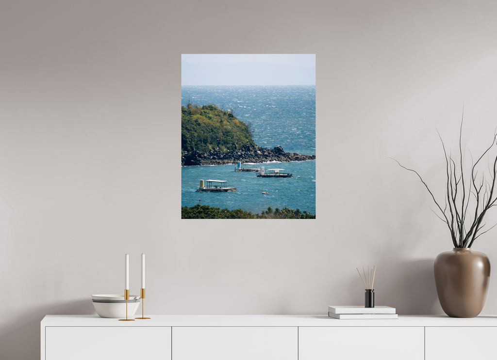 Wall art of a coastal scene with boats on a plain wall above a white cabinet.