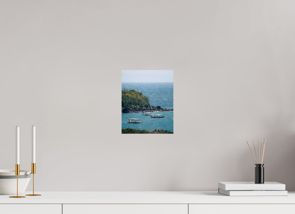 Unframed artwork of a coastal scene with boats on a white wall above a white shelf.