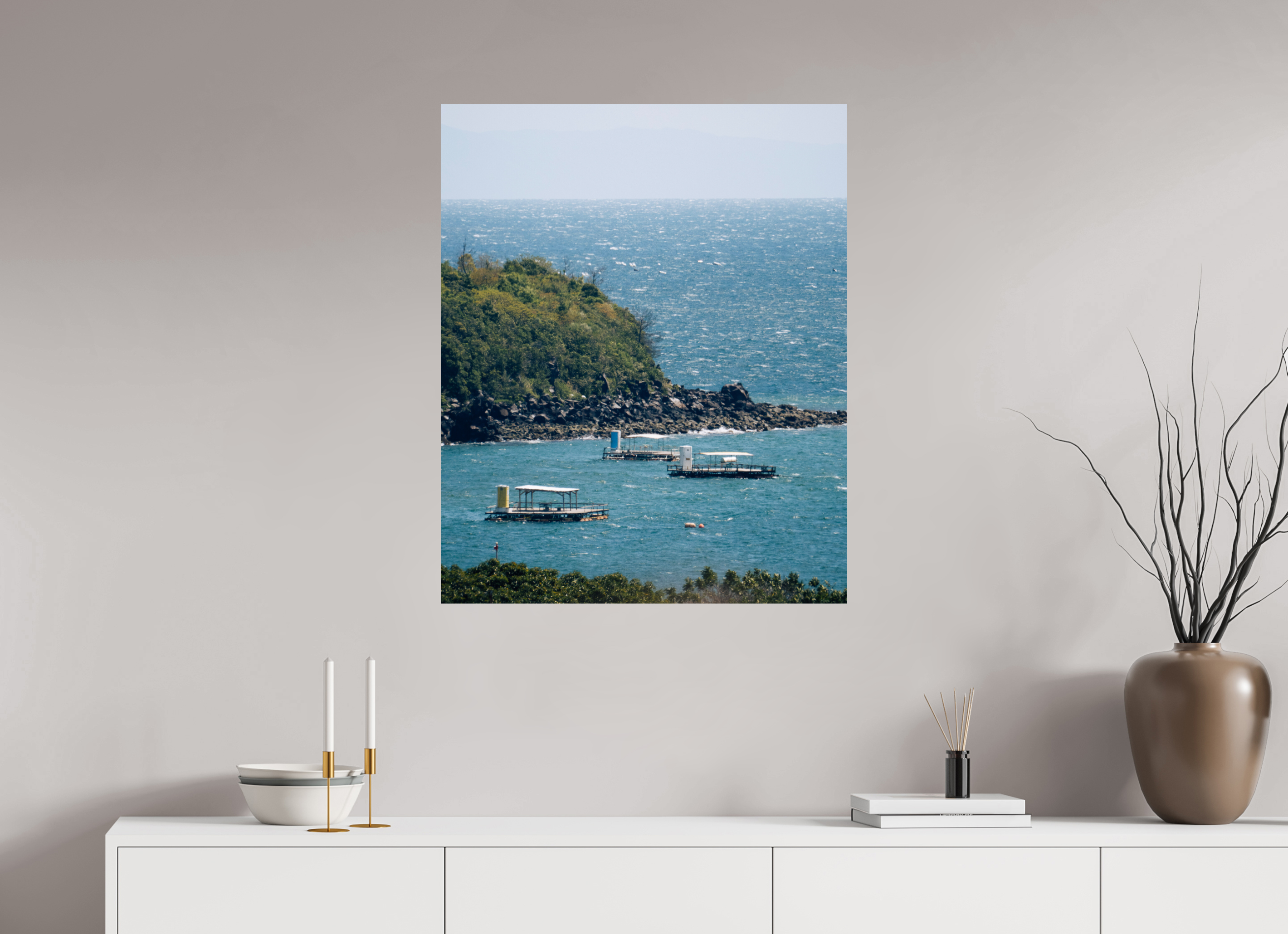 Wall art of a coastal scene with boats on a white wall above a white cabinet.