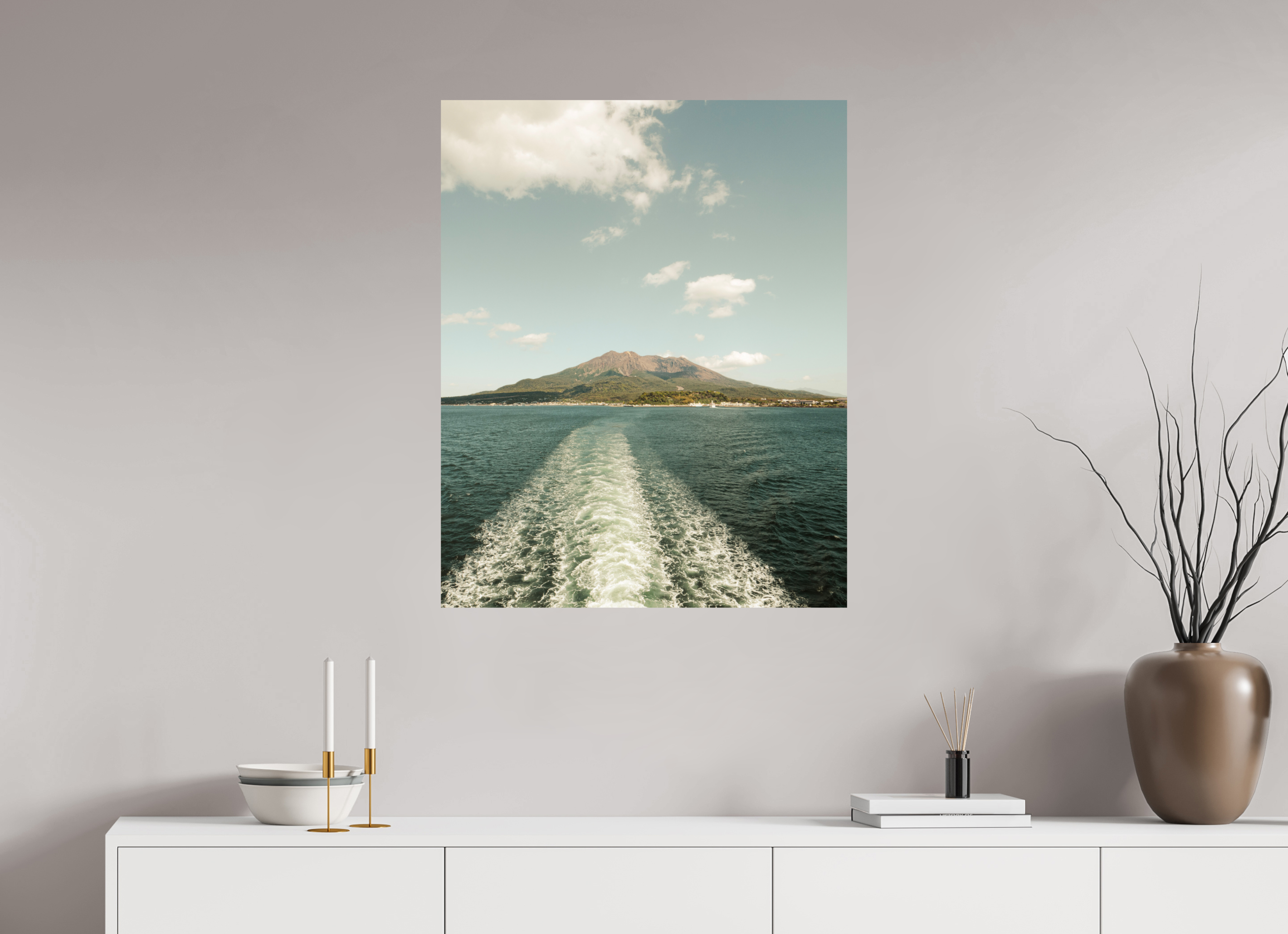 Wall art of a scenic view of water and mountains on a gray wall above a white console table.