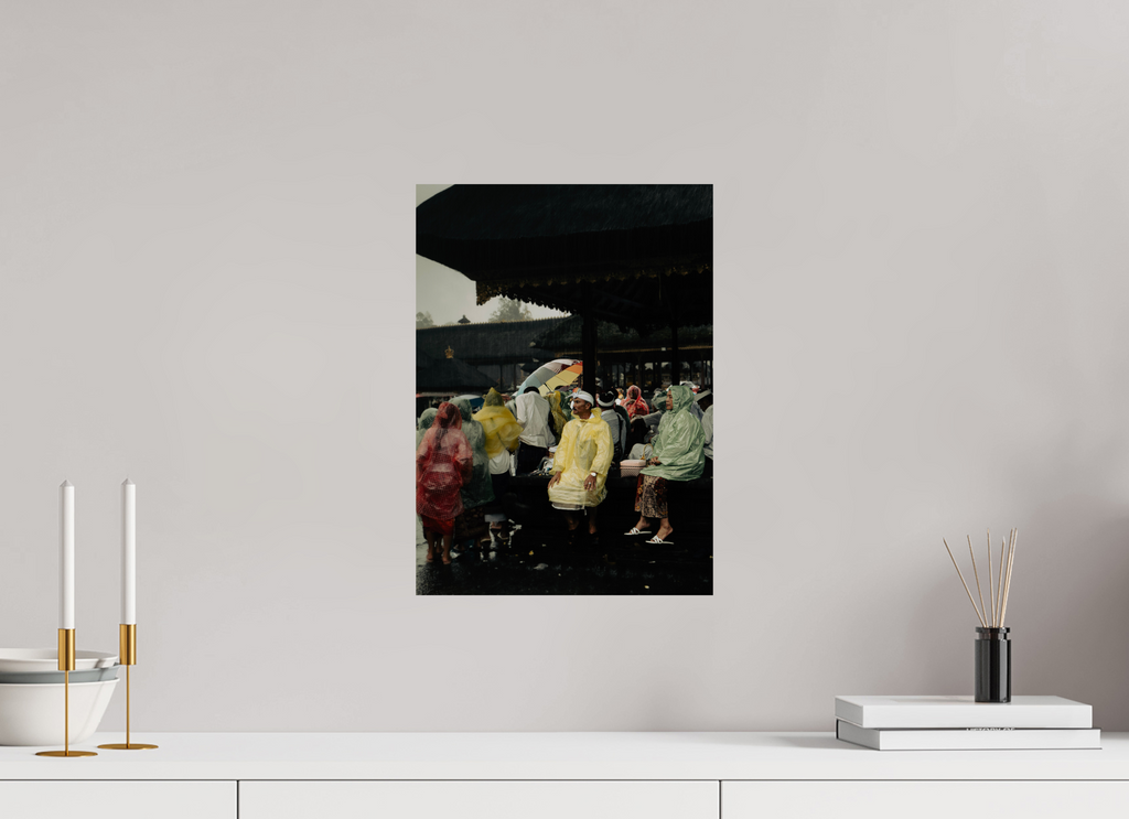 Unframed artwork on a wall above a white surface with decorative items. Focuses on people sitting out the rain at a temple on ceremony day.