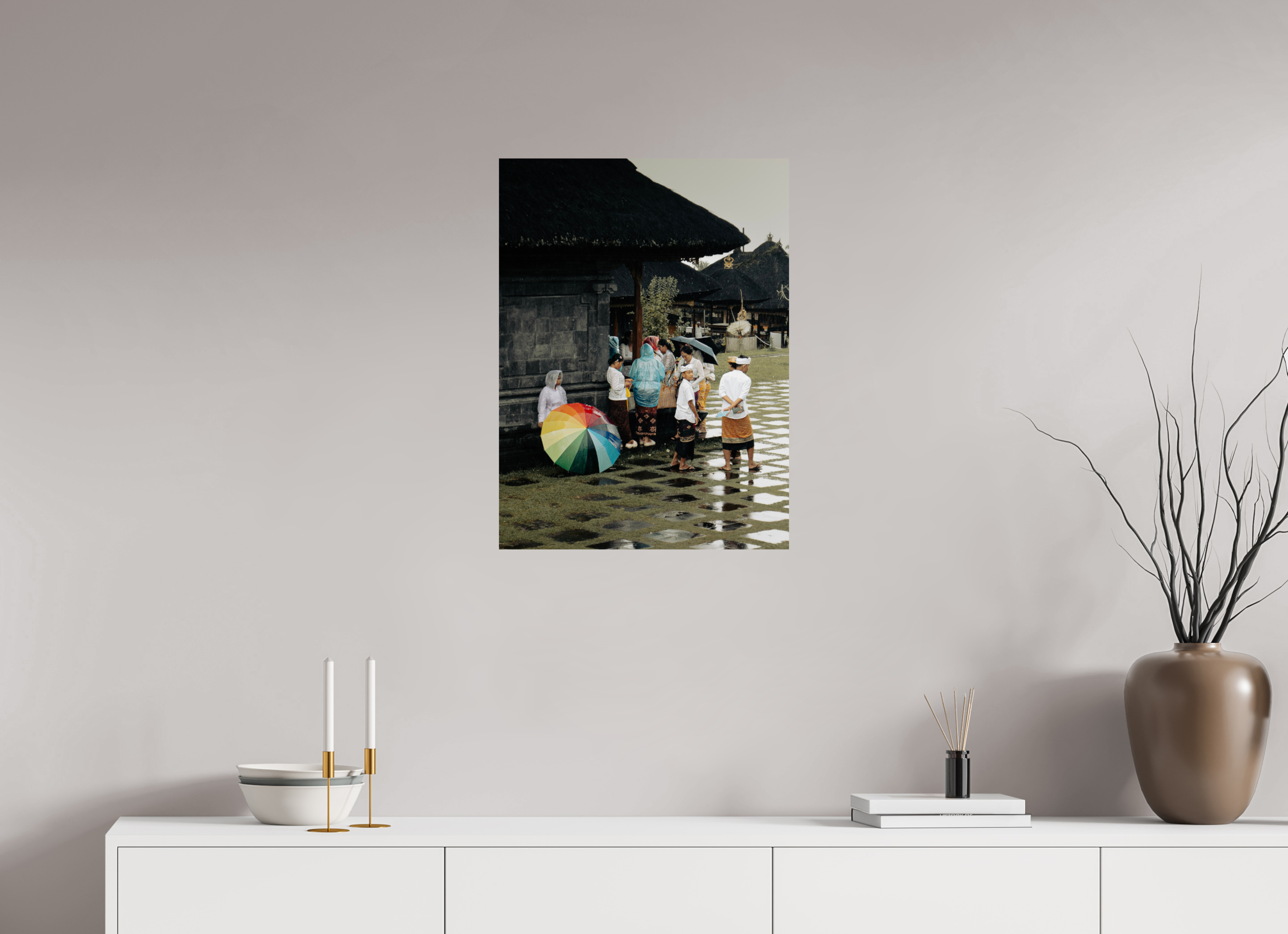 Framed photograph of a family with a rainbow umbrella on a wall above a white surface with decorative items.