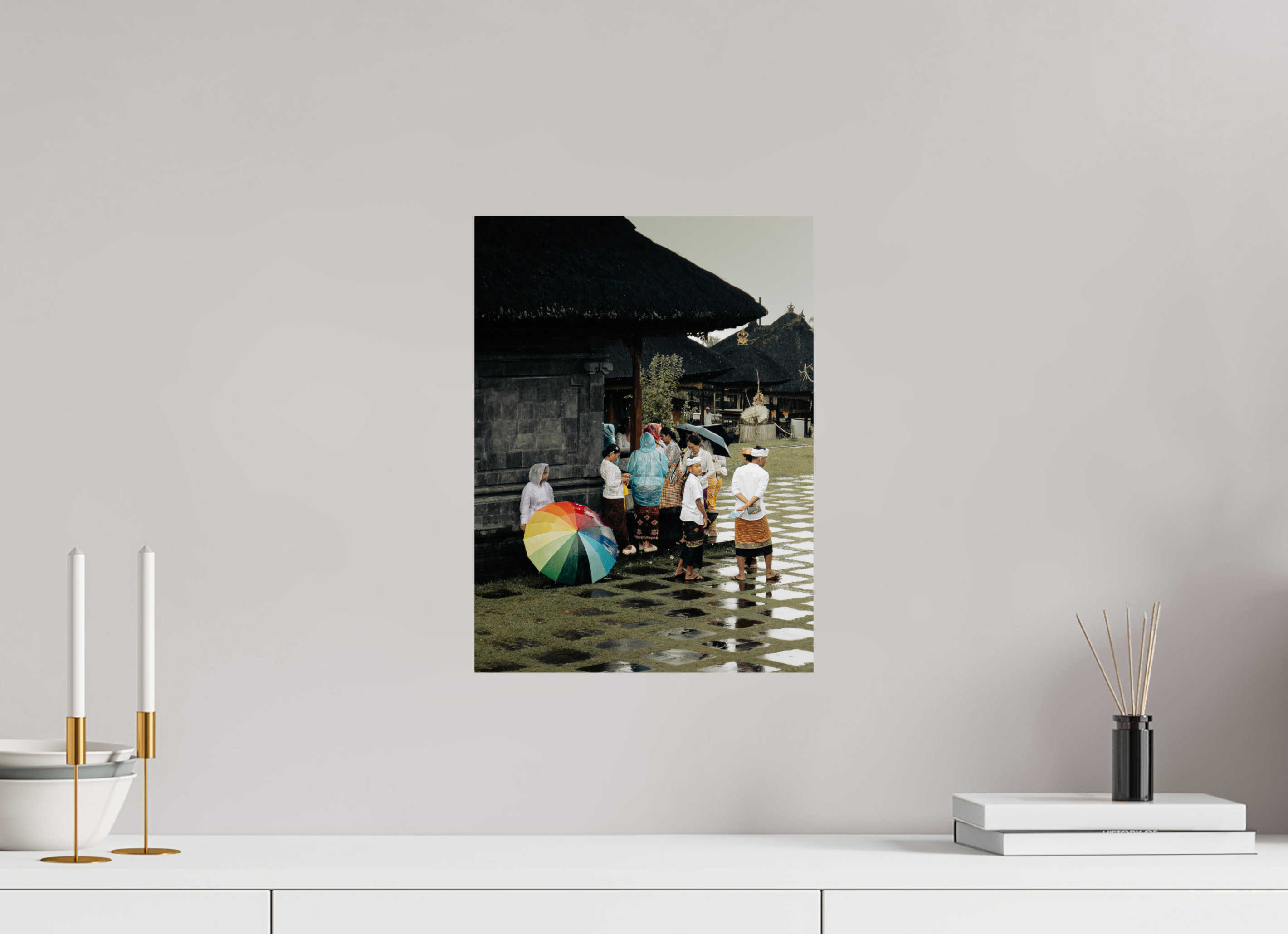Framed photograph of a family with a rainbow umbrella on a wall above a white surface with decorative items.