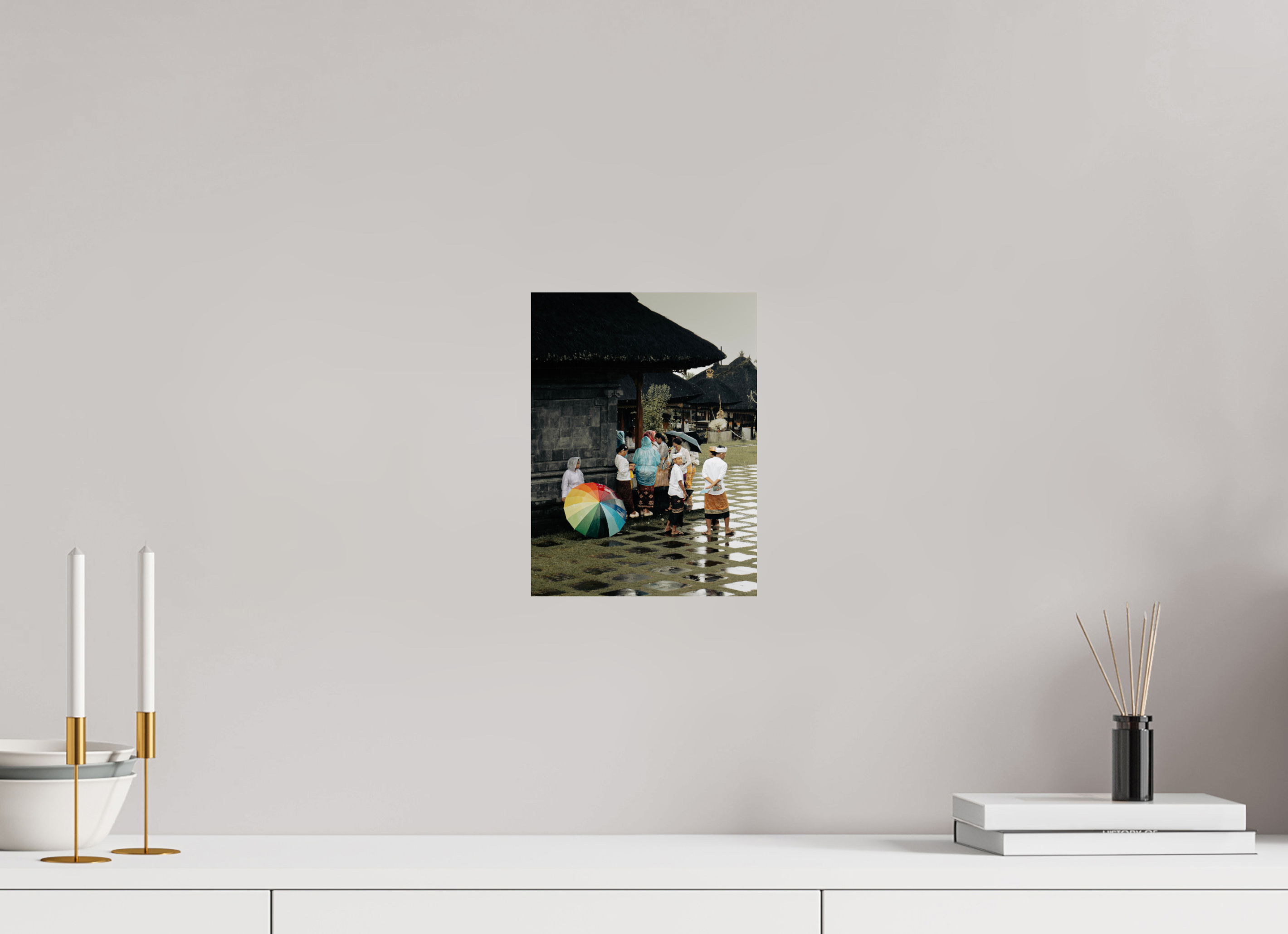 Framed photograph of a family with a rainbow umbrella on a wall above a white surface with decorative items.